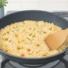 冷凍チャーハンをフライパンに広げて木べらで温める様子
