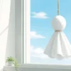 晴れた空を望む窓辺に吊るした白いてるてる坊主