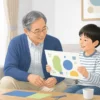 孫が見せる工作を祖父が笑顔で見守る様子