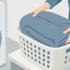 洗濯前の毛布をかごに入れて準備する手元