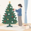室内でクリスマスツリーにオーナメントを飾る様子
